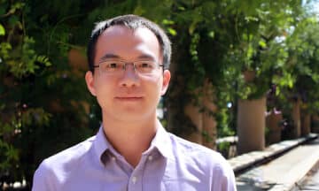 A headshot of Chao Chen standing outside in front of some trees.