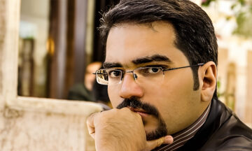 A headshot of Hossein Tohidi standing in front of a building.