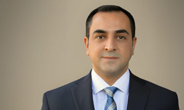 A headshot of Mohammad Hosseinian standing in front of a light brown background.