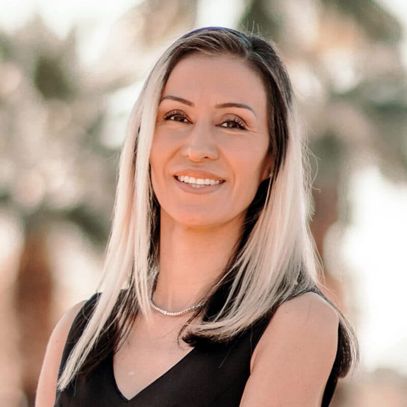 A headshot of Erika Tatiana Camacho standing in front of some palm trees.