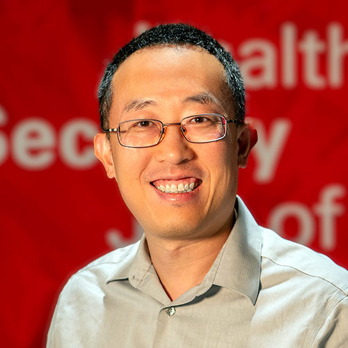 A headshot of Renran Tian standing in front of a red background in Fitts-Woolard Hall.