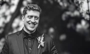 A black and white headshot of Patrick Leavitt standing in front of some trees.