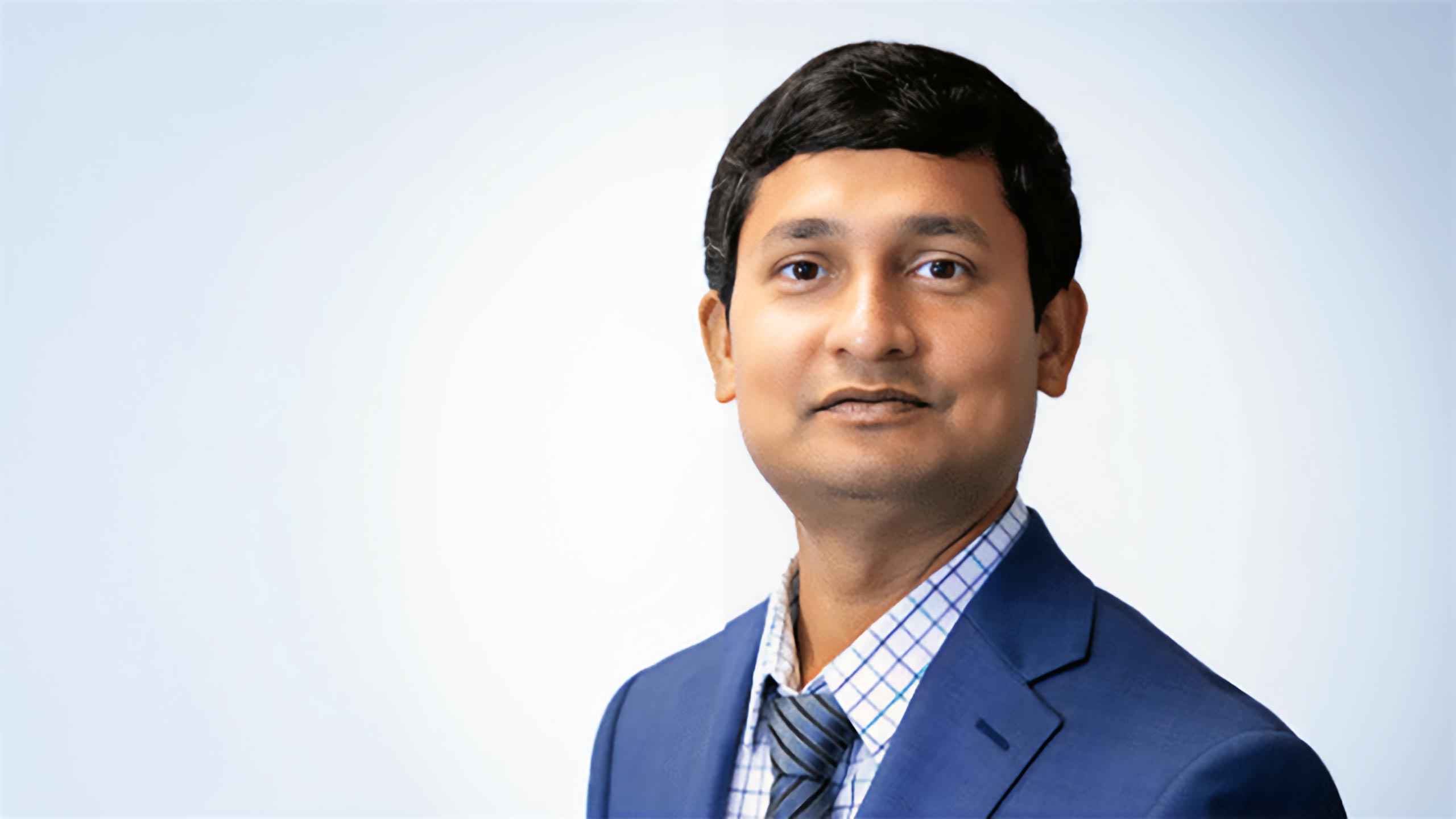 A headshot of Md Abdul Quddus standing in front of a light blue background.