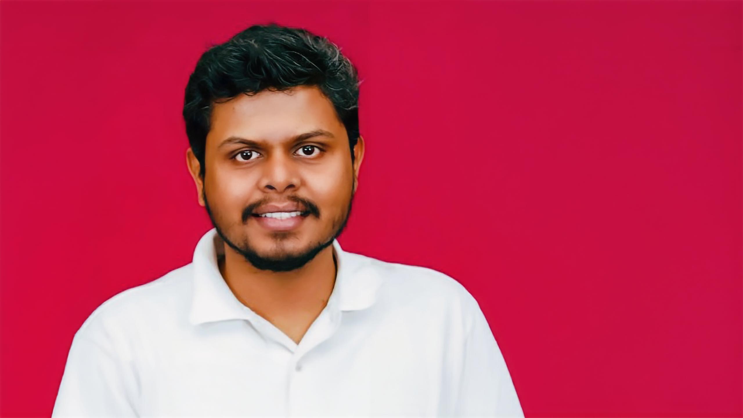 A headshot of Subramanian Pazhani standing in front of a red background.