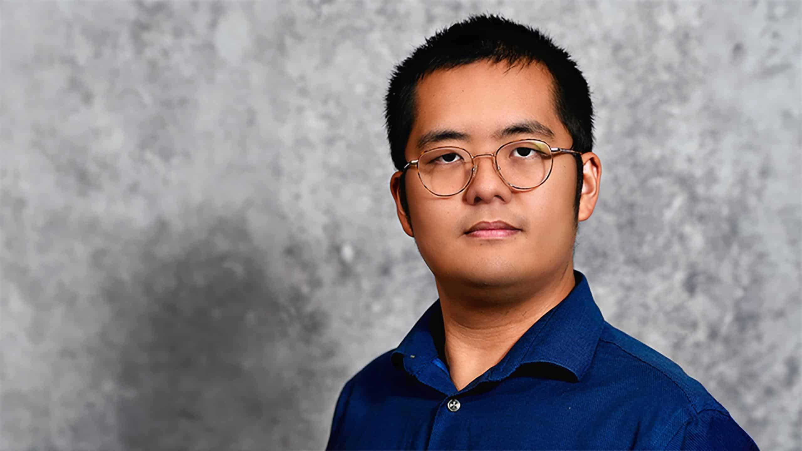 A headshot of Wentao Tang standing in front of a gray marbled background.