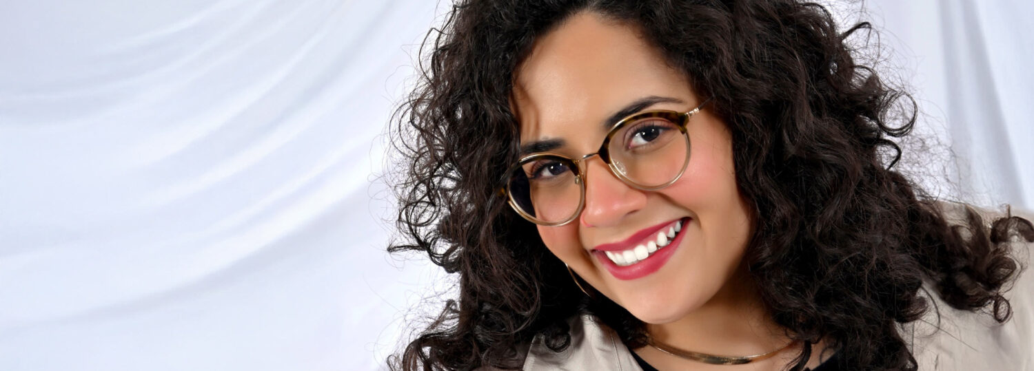 A headshot of Laura Mora standing in front of a white background.