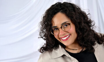 A headshot of Laura Mora standing in front of a white background.